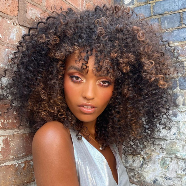 fall 2021 hair color trends warm caramel curly hair brunette