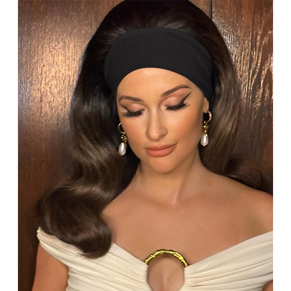 Kasey Musgraves get the look from Schiaparelli Spring 2024 runway show at Paris Couture Fashion Week. She was wearing a glamorous bouffant hairdo and thick black headband for extra drama.