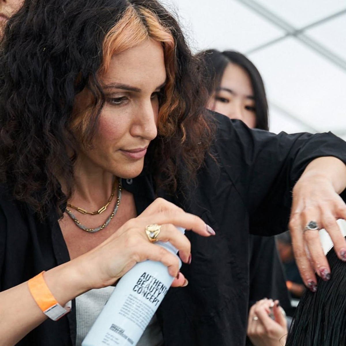 Anna Cofone spraying someone's hair wearing a black shirt.