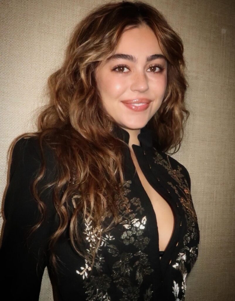 Mika Abdalla with bronzed brown hair featuring honey ribbon highlights, styled in soft, tousled waves with face-framing dimension and a layered shag.